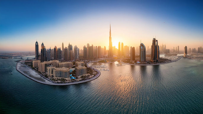 A stunning panoramic view of Dubai's skyline at sunset, showcasing iconic skyscrapers like the Burj Khalifa and luxurious waterfront properties.