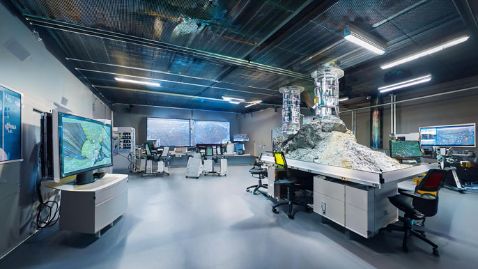 A clean energy lab with advanced equipment and researchers analyzing sustainable mining technologies, featuring a metallic ore sample and digital displays.